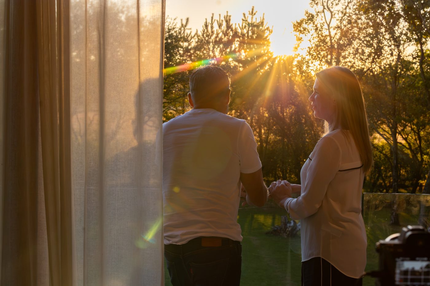 A couple silhouetted against the sunset through the balcony window at Warren House