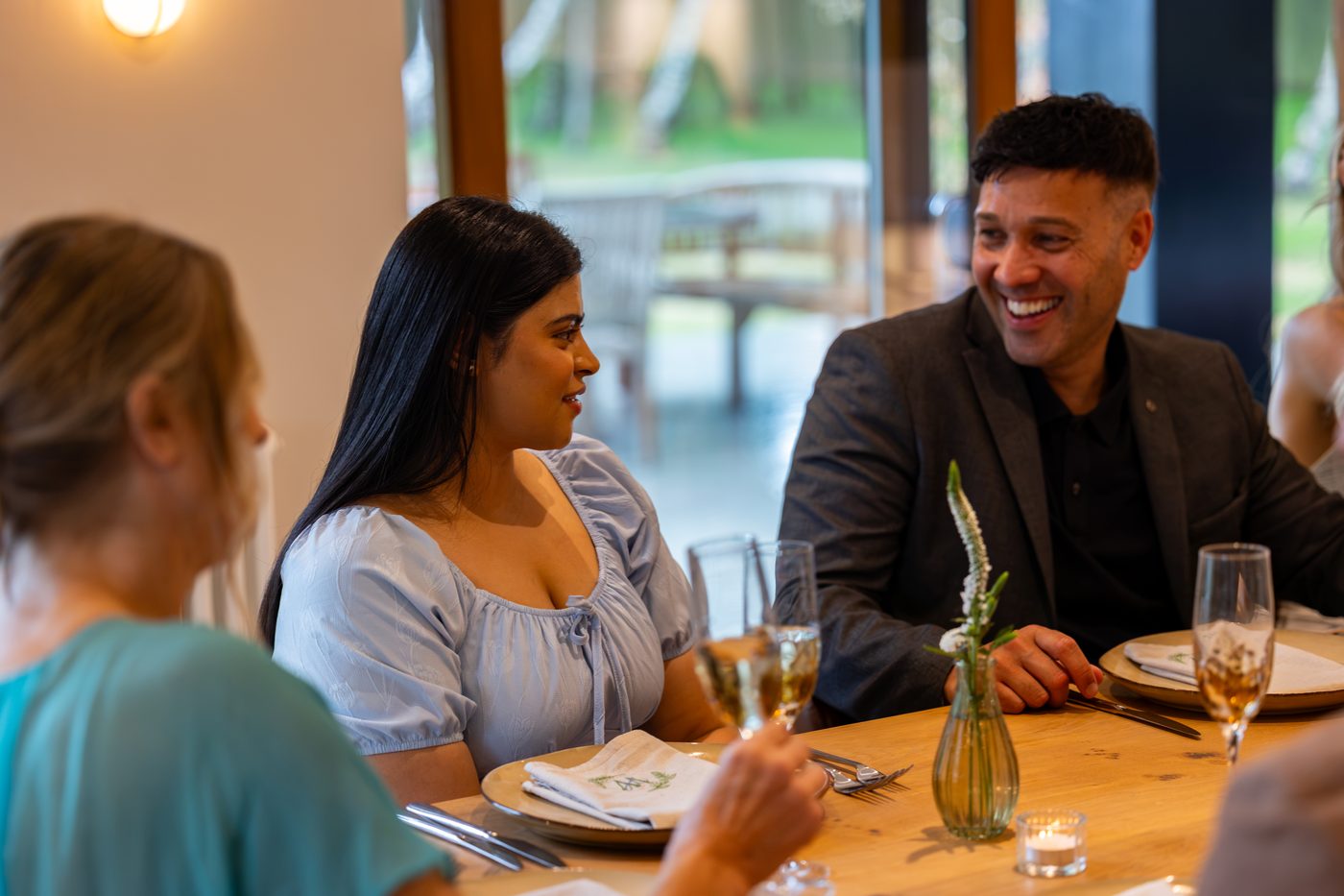 Guests laughing over dinner at the long oak dining table at Warren House