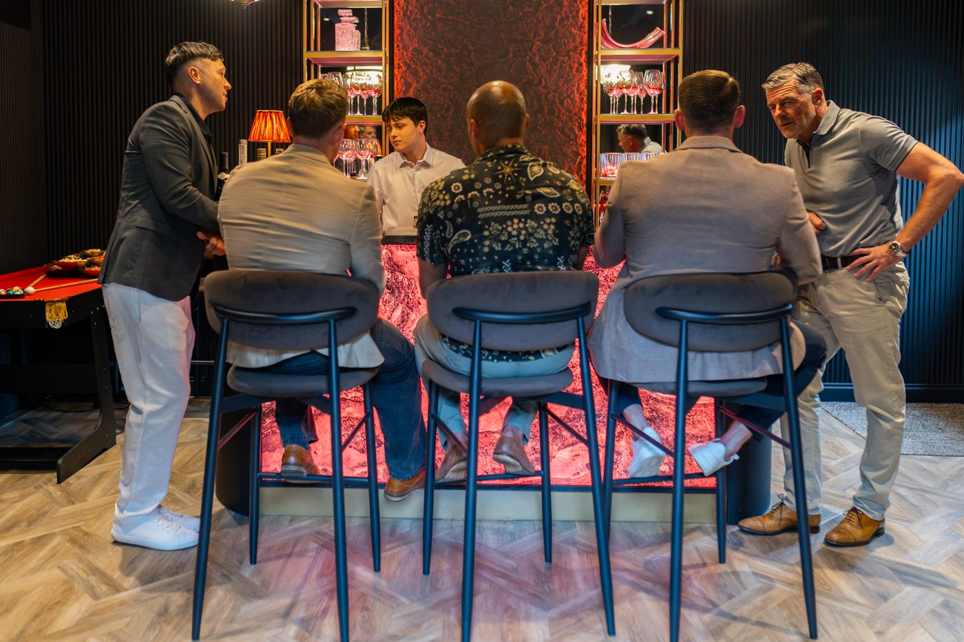 Friends on stools at the marble bar at Warren House with the pool table behind