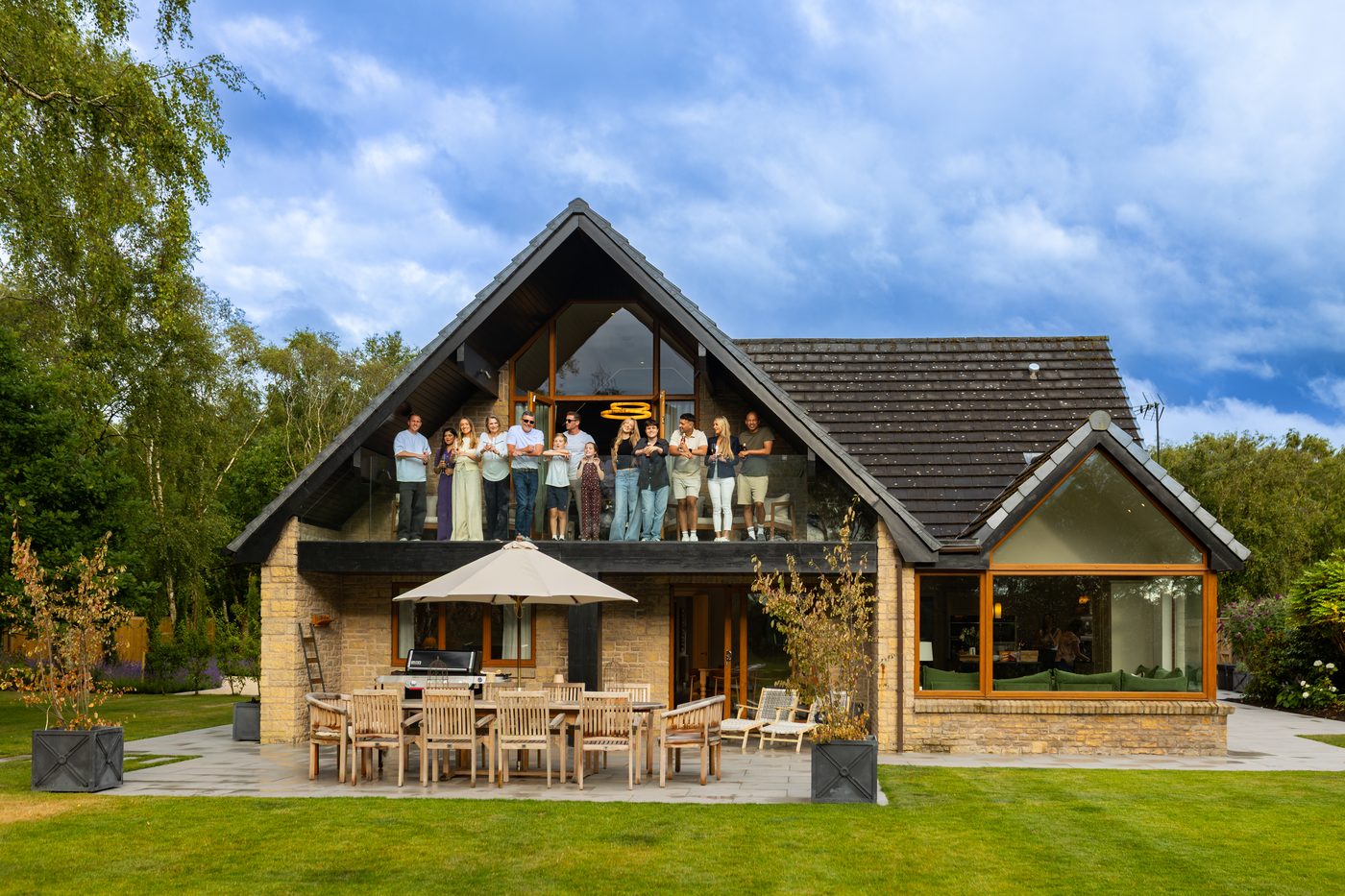 The whole group waving from the balcony of Warren House with the gardens all around