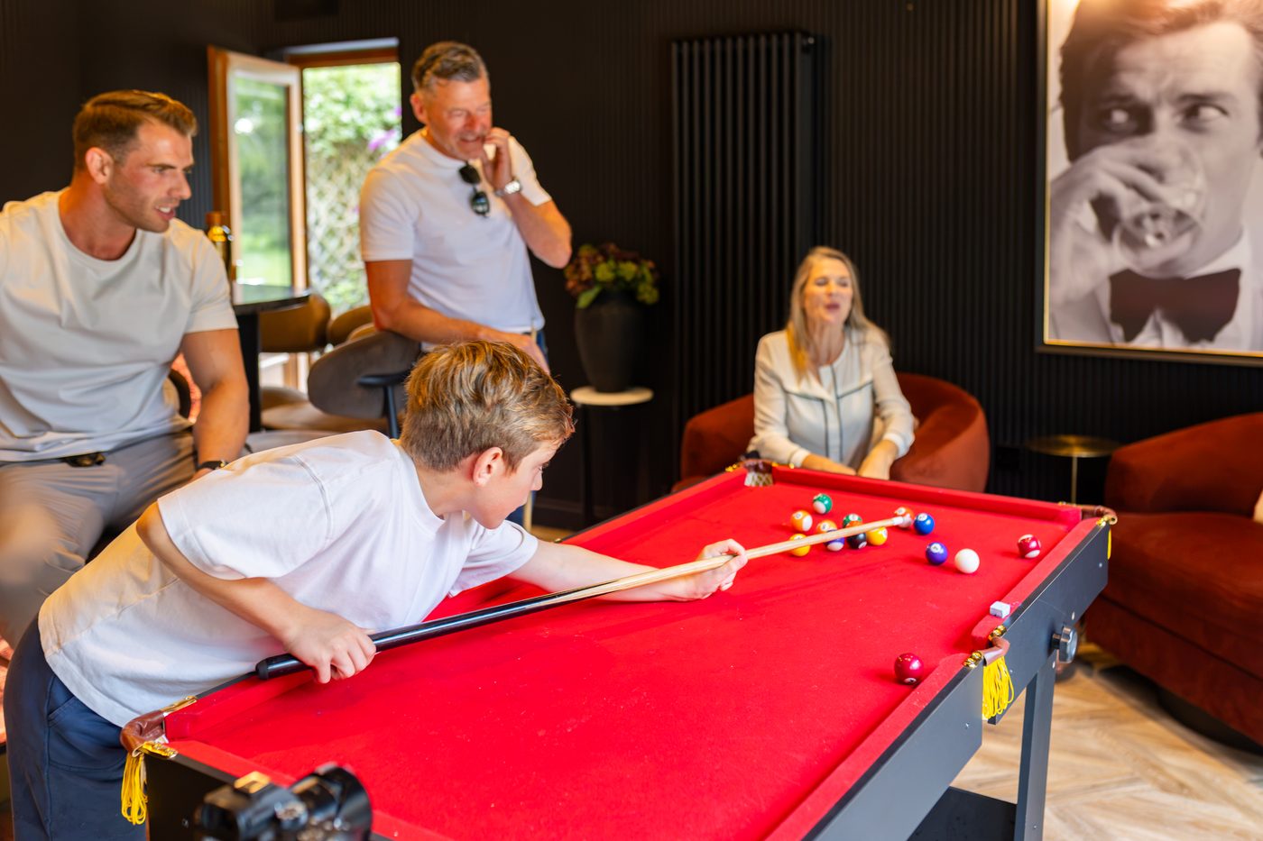 A family game on the red pool table in the bar at Warren House